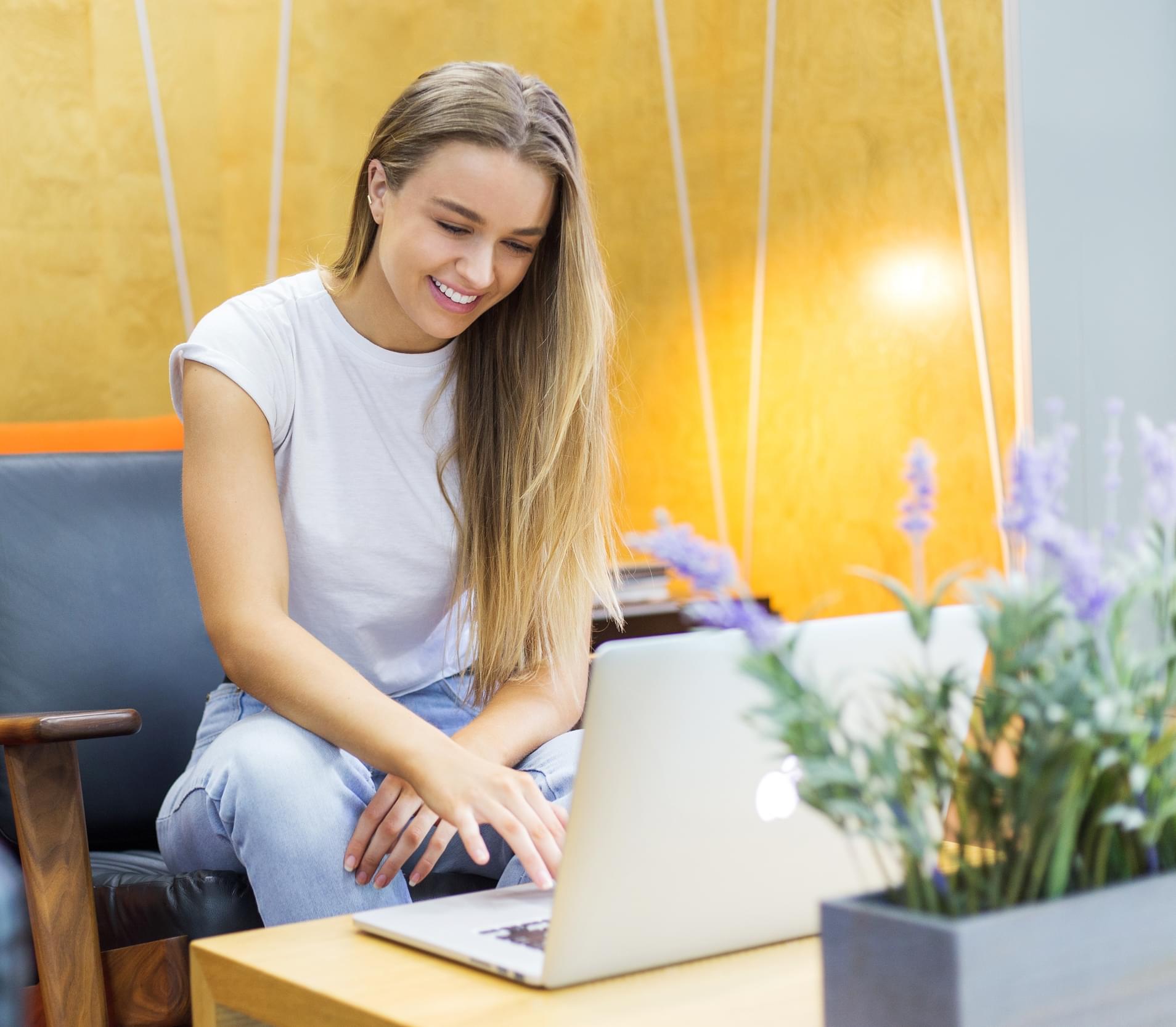 A female sitting looking at a laptop